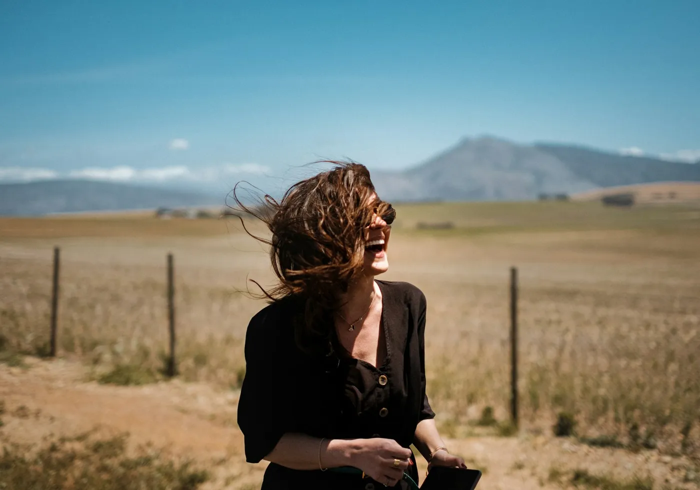 A woman laughing freely in an open field